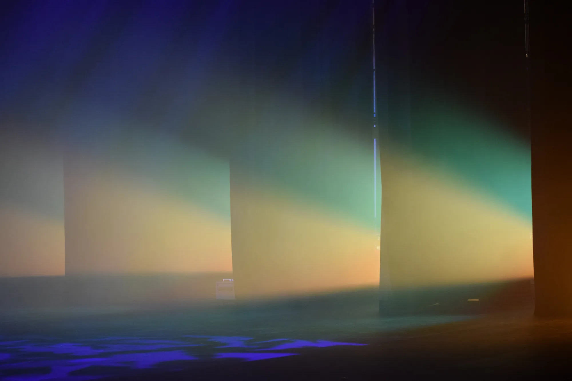 Arangetram stage with green and amber lighting through haze and blue patterns on the floor