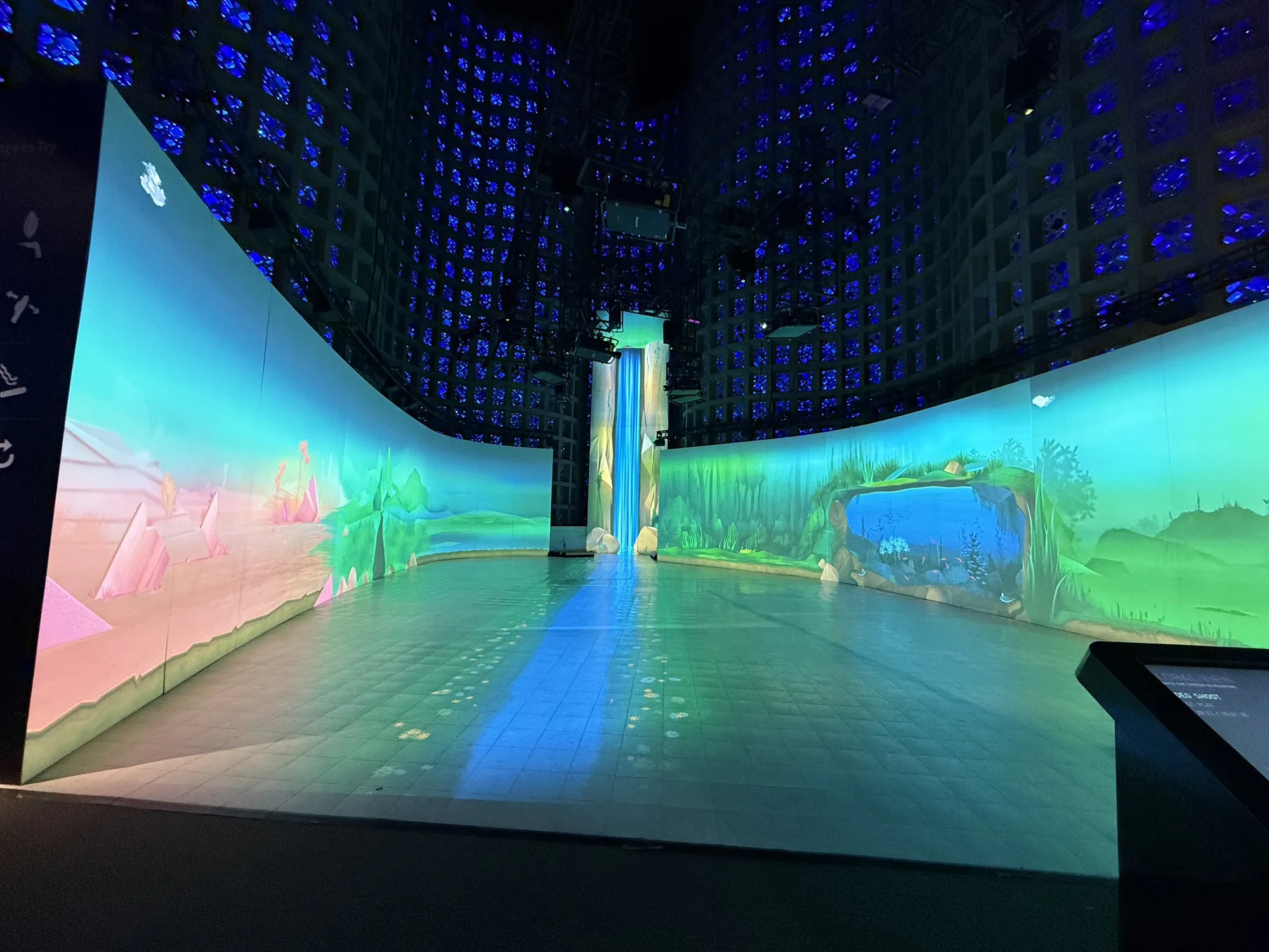 Curved walls filled with colorful landscape projections beneath blue ceiling lights at the WGU alumni celebration